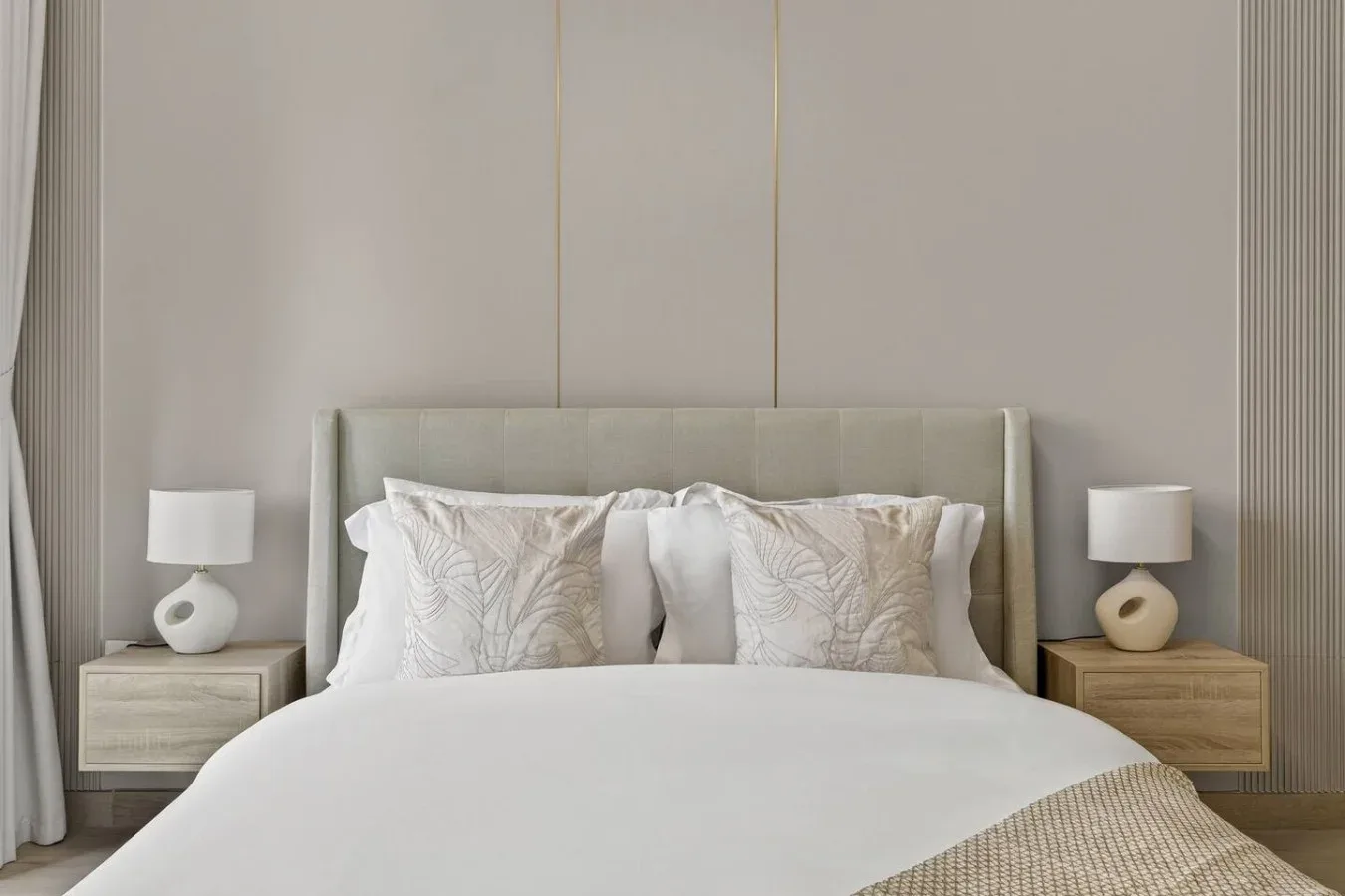 A neatly made bed with patterned pillows and matching bedside lamps.