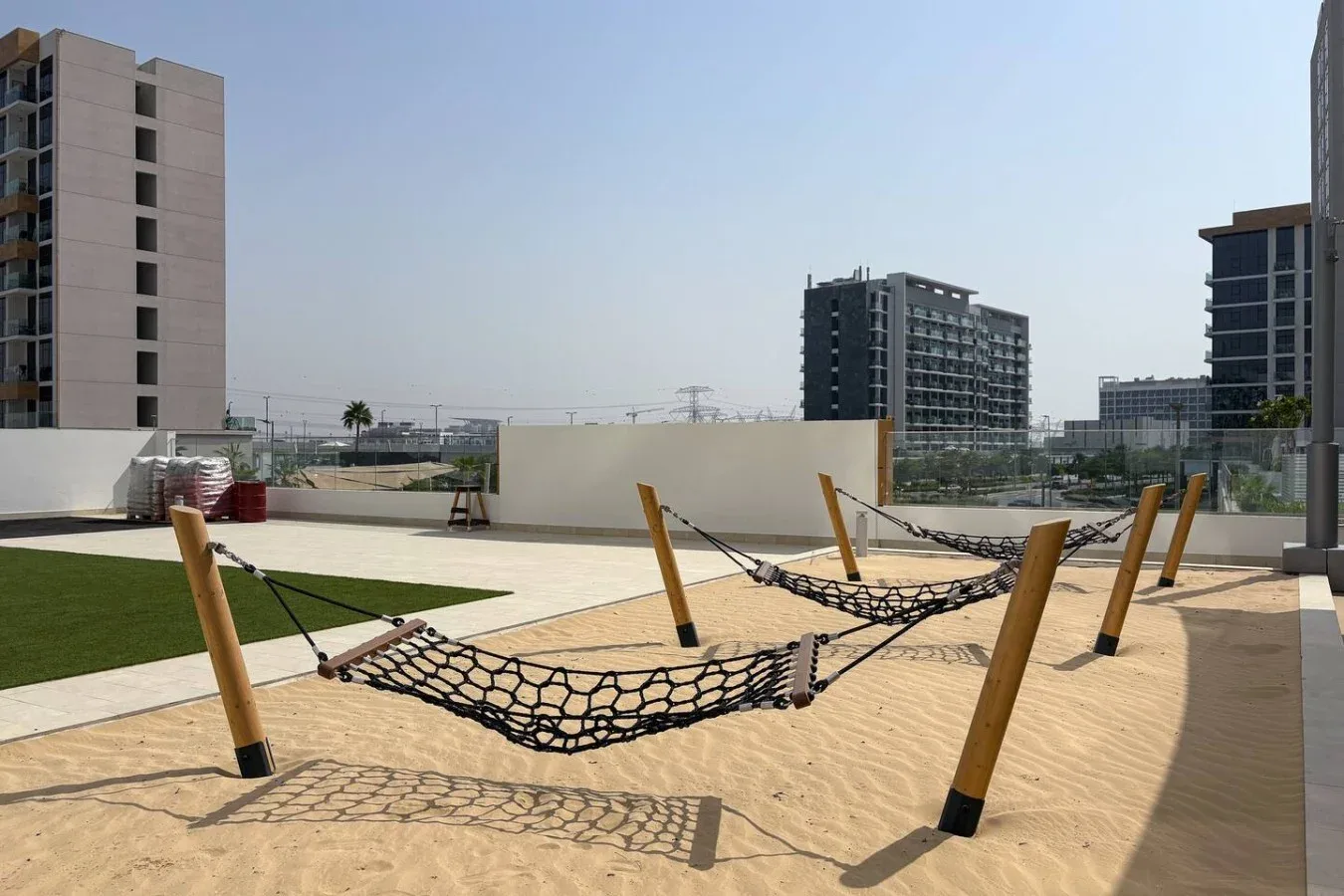 An outdoor rooftop terrace with hammocks suspended over a sandy area.