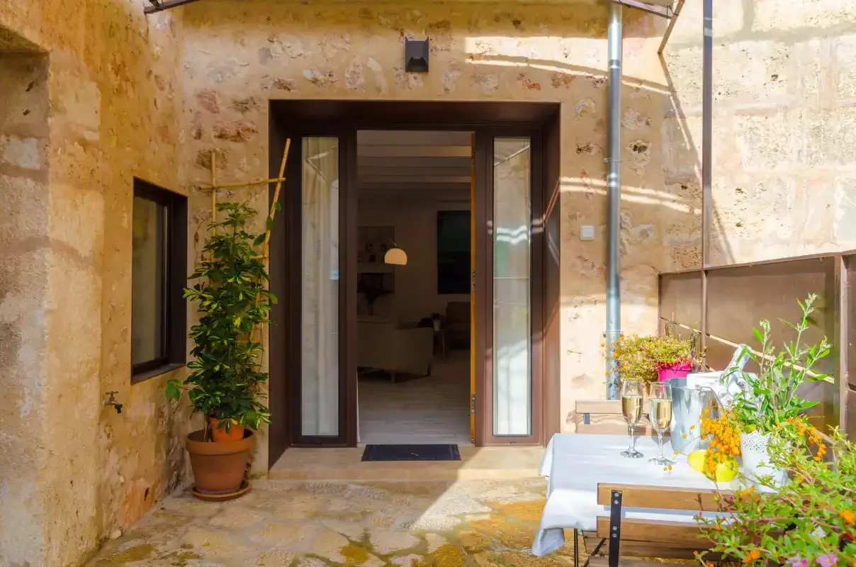 A stone patio with an open glass doorway and a dining table.