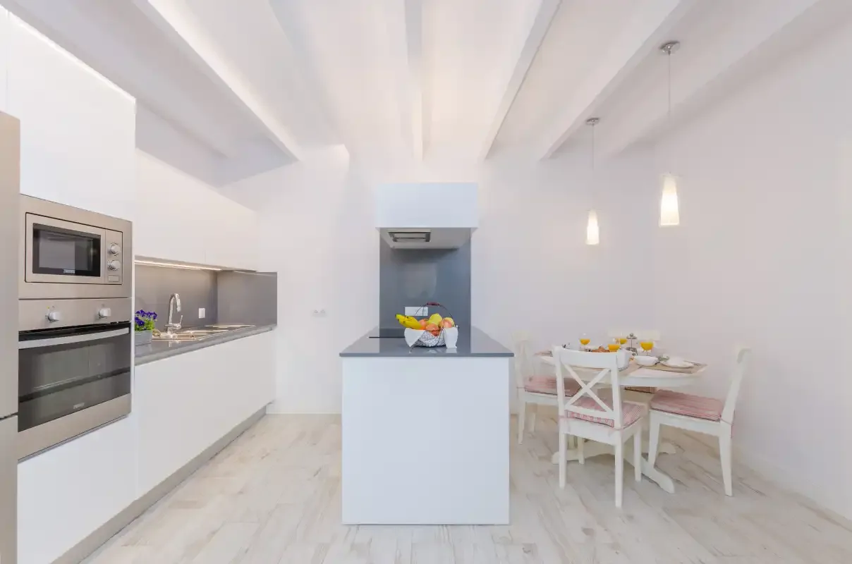 A bright kitchen with a central island and a dining table.