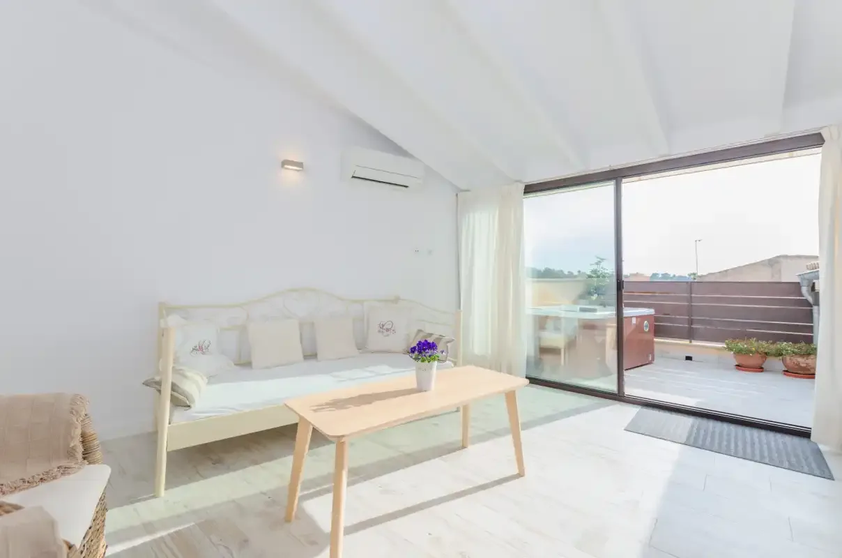 A bright living area with a daybed, coffee table, and sliding glass doors opening to a terrace.
