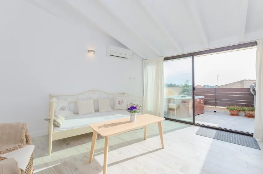 A bright living room with seating, a coffee table, and sliding glass doors to a terrace.