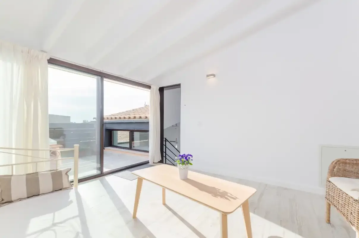 Bright living area with a low wooden table beside large sliding glass doors.