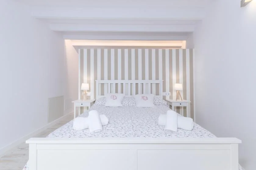 A bright bedroom with a bed set against a striped accent wall.