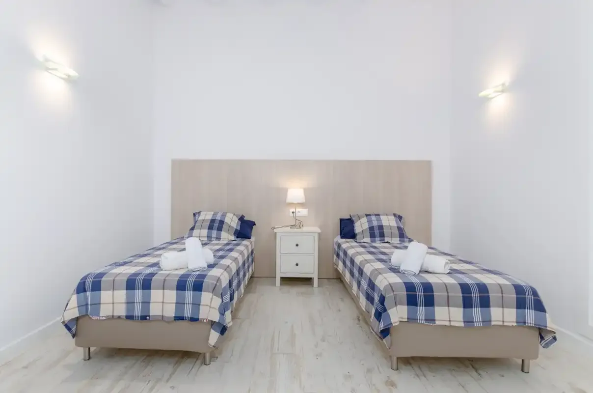A bright bedroom with two beds dressed in blue plaid bedding.