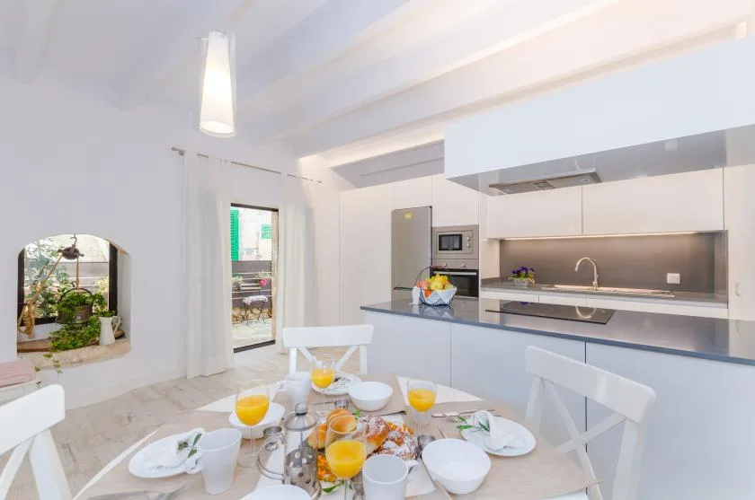 A bright open-plan kitchen and dining area with a table set for a meal.