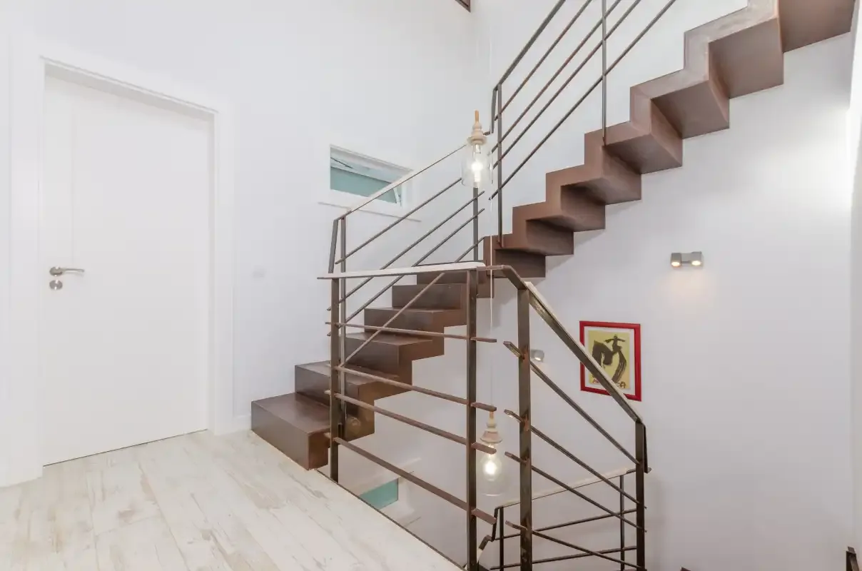 A bright interior stairwell with a dark staircase and metal railings.