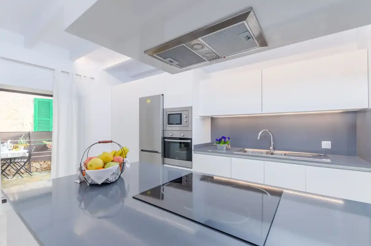 A bright modern kitchen with white cabinets, a countertop, and a cooktop.