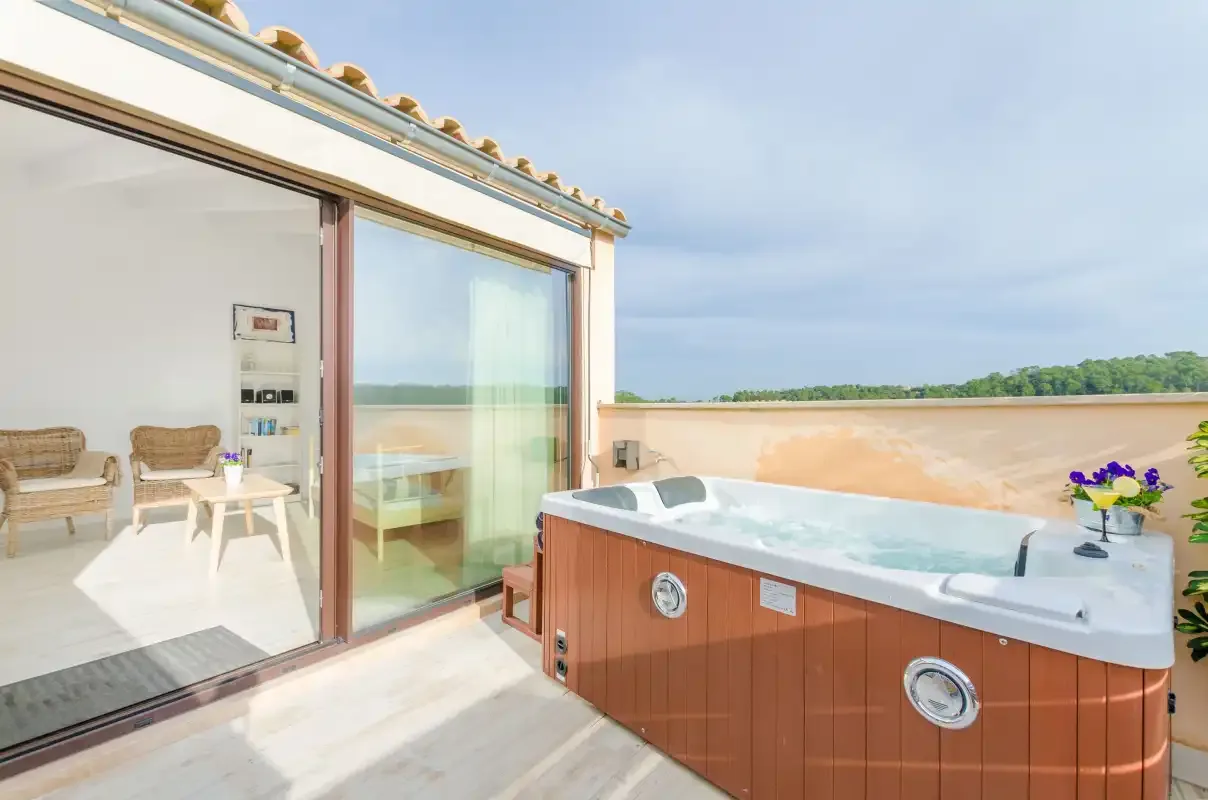 A rooftop terrace with a hot tub beside a glass sliding door.