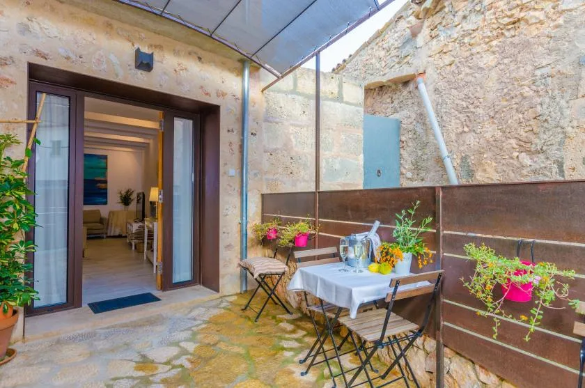 A stone courtyard patio has a table and chairs beneath a translucent canopy.