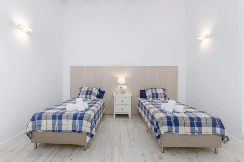 A bright bedroom with two beds and a small nightstand between them.