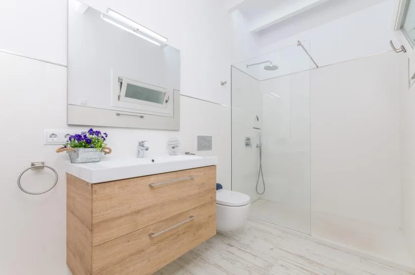 A bright bathroom with a wood-finish vanity and glass shower.