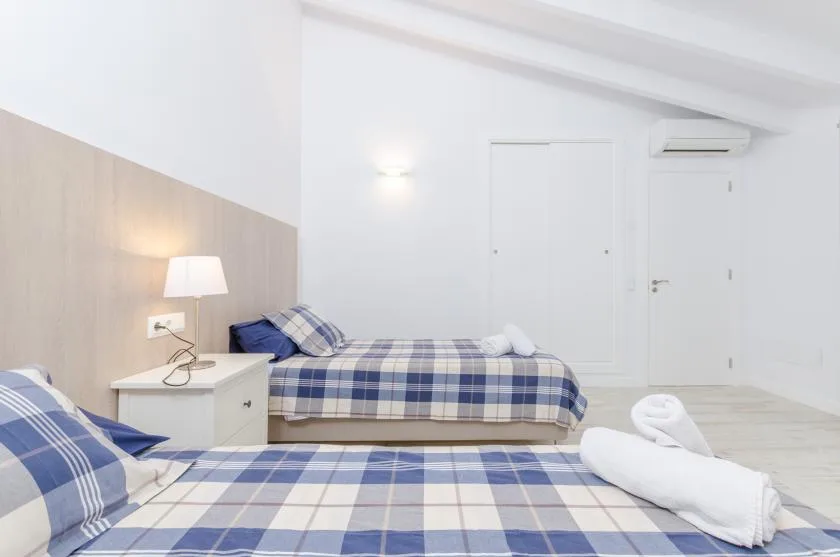 A bright bedroom with two beds dressed in blue plaid bedding.