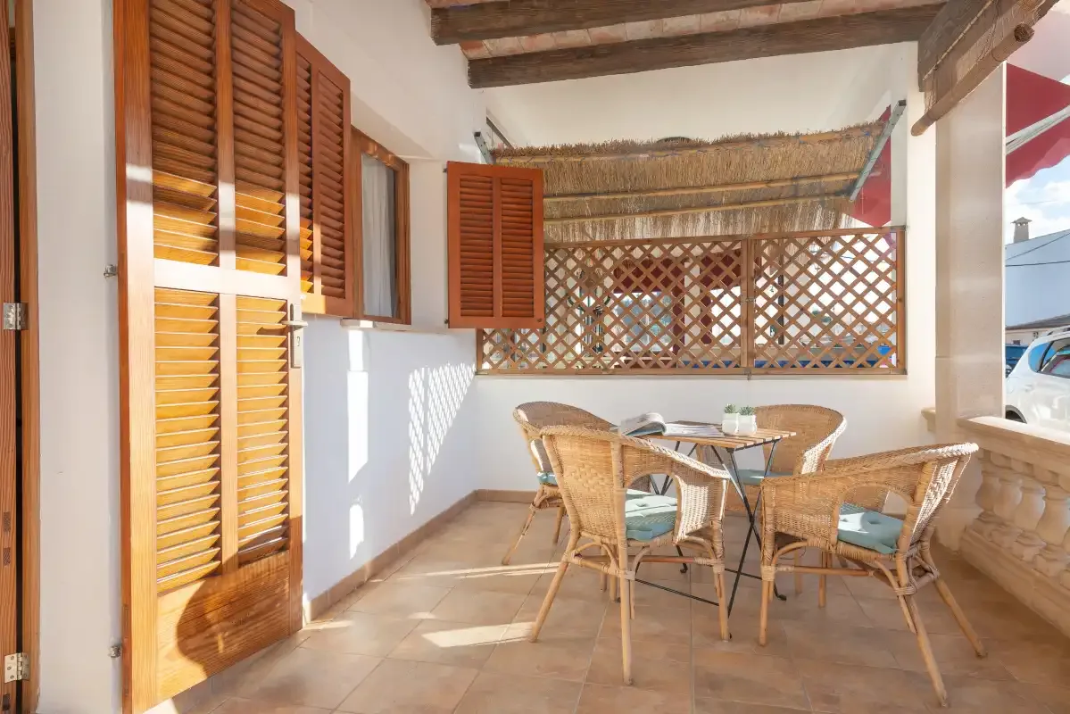 A covered patio has wicker seating around a glass-topped table.