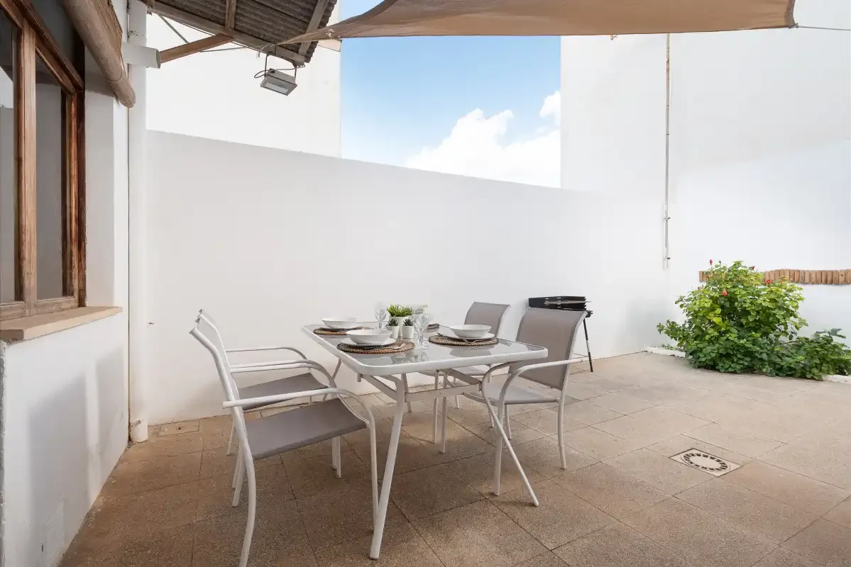 An outdoor dining area with a table and chairs on a tiled patio.