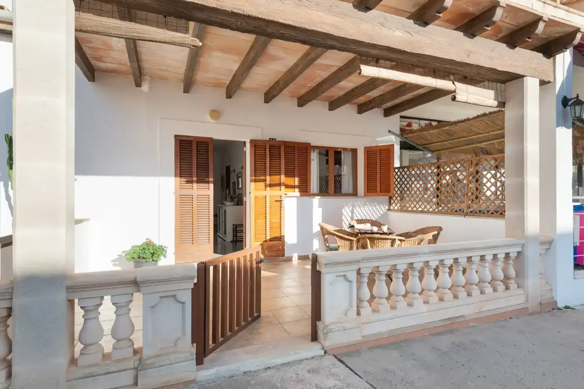 A covered patio with wooden ceiling beams and an open doorway.