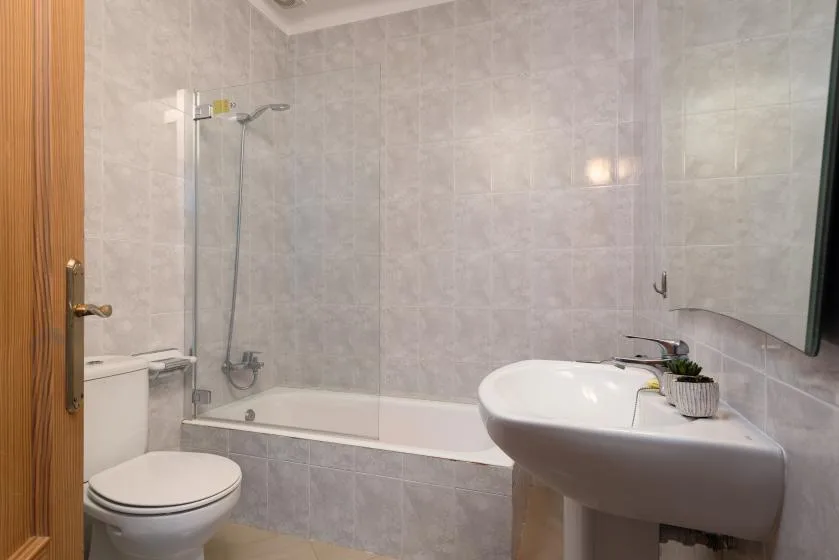 A tiled bathroom with a bathtub, toilet, and pedestal sink.