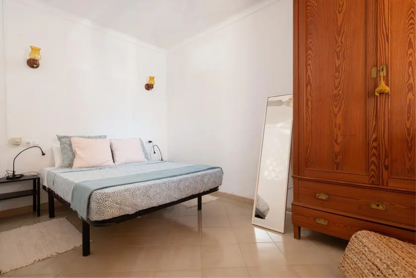 A bedroom with a bed, bedside table, and wooden wardrobe.