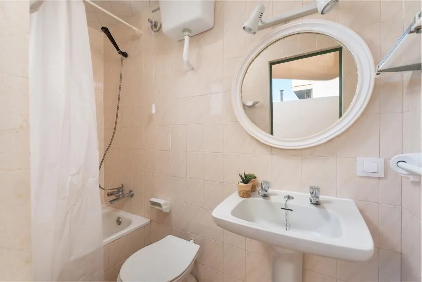 A tiled bathroom with a sink, mirror, and shower curtain.