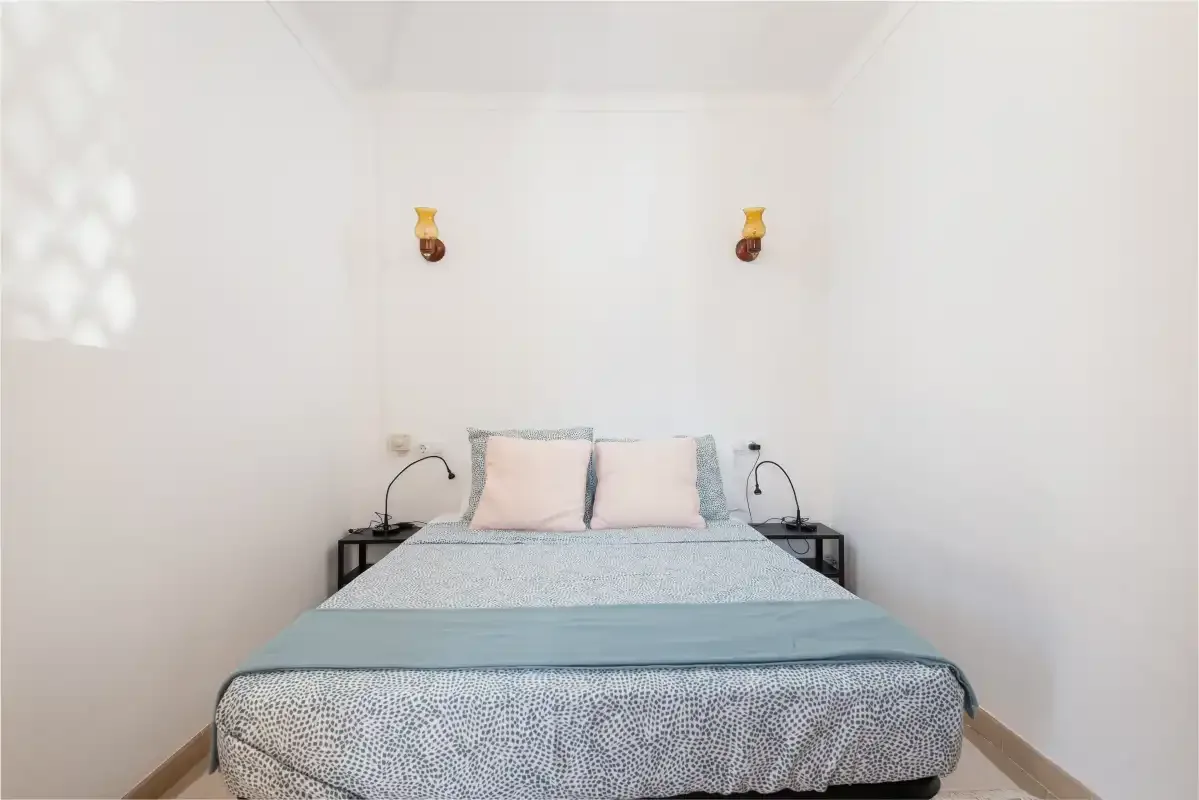 A bedroom with a bed and matching wall lights.