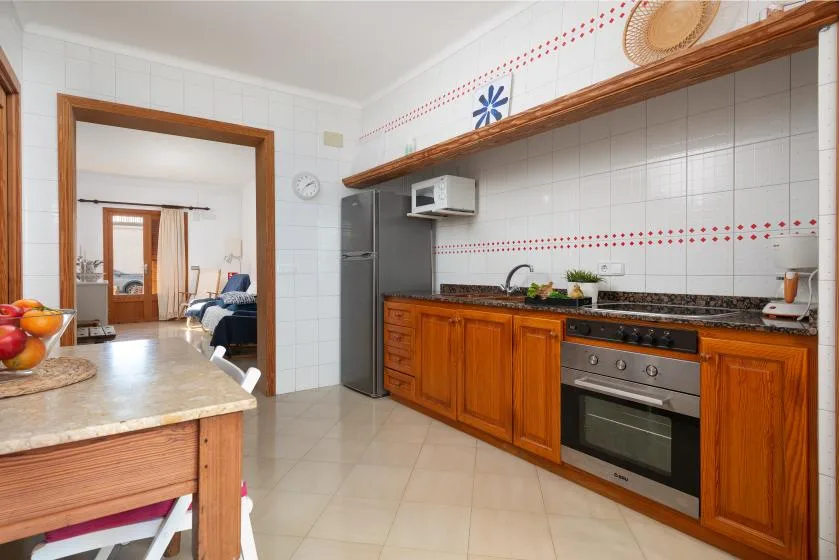 A tiled kitchen with wooden cabinets, a countertop, and an oven.