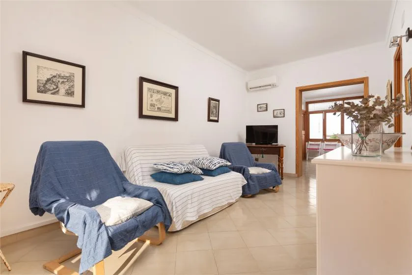 A bright living room with seating, a television, and a doorway to another room.