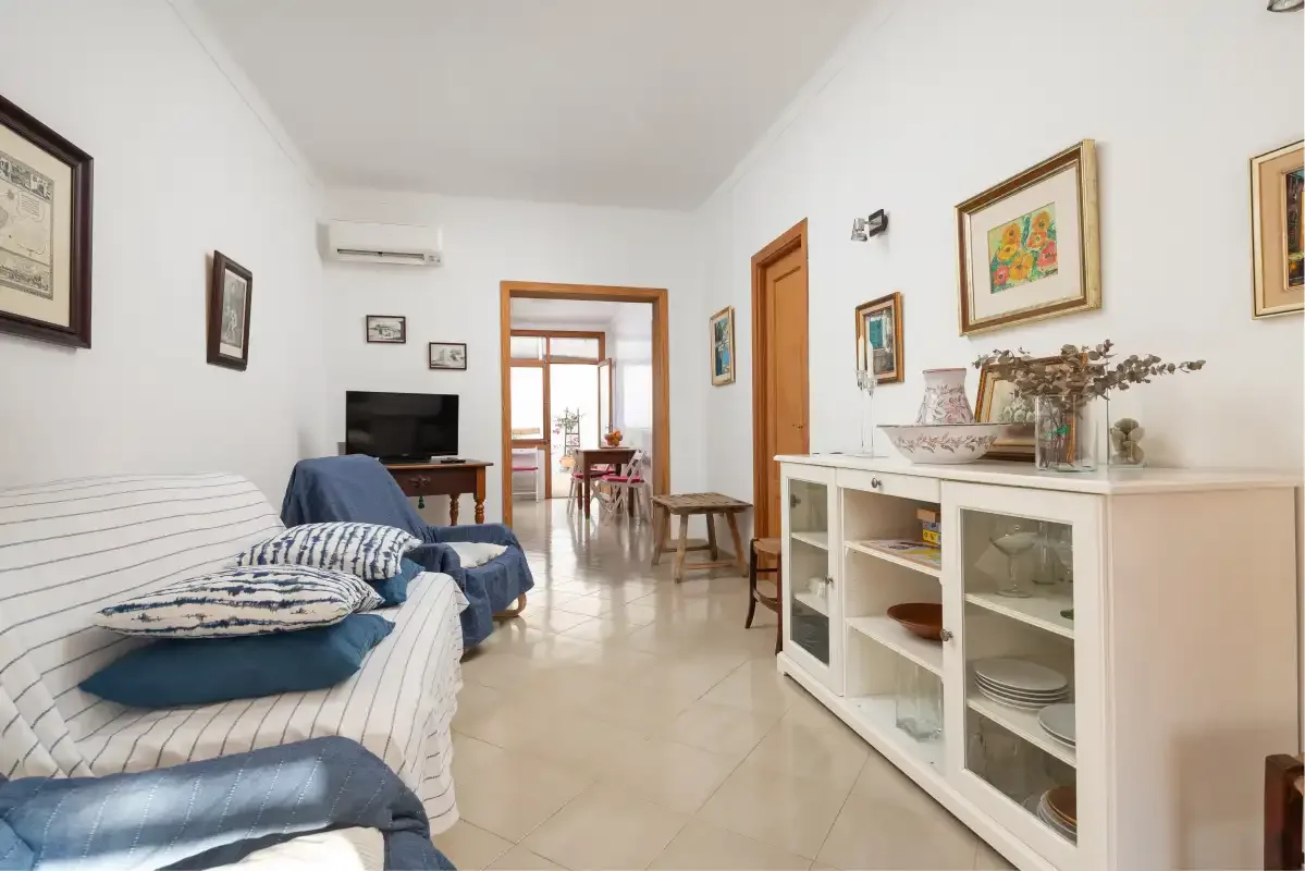 A bright living room with seating, a television, and a white display cabinet.