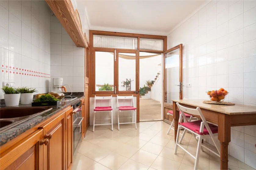 A tiled kitchen and dining area with wooden cabinets, a table, and chairs.