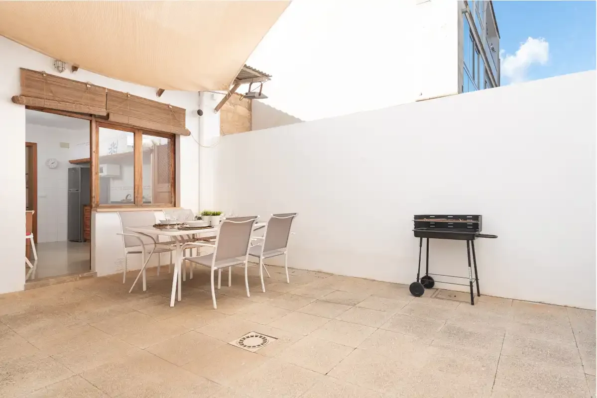 A tiled patio with a dining table and a small grill.