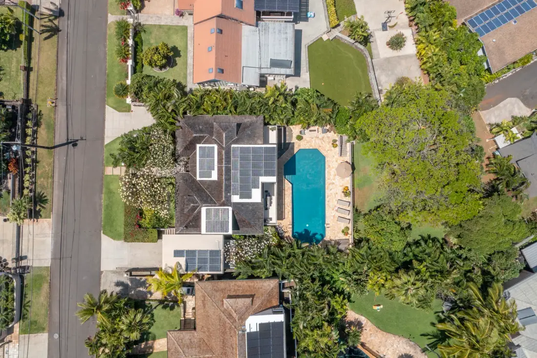 Aerial view of a house with a swimming pool and surrounding gardens.