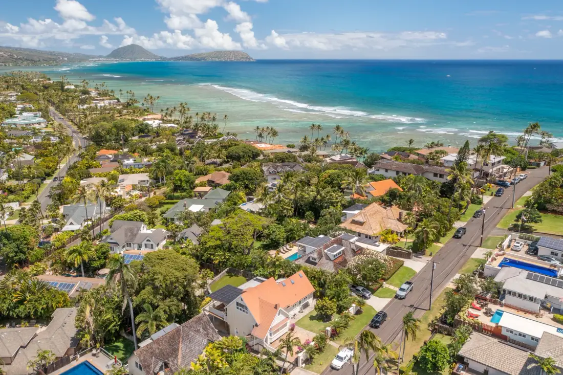 Aerial view of a coastal neighborhood beside a turquoise ocean.