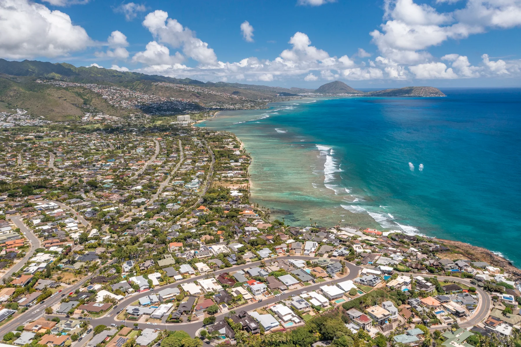 An aerial view of a coastal neighborhood beside a turquoise bay.