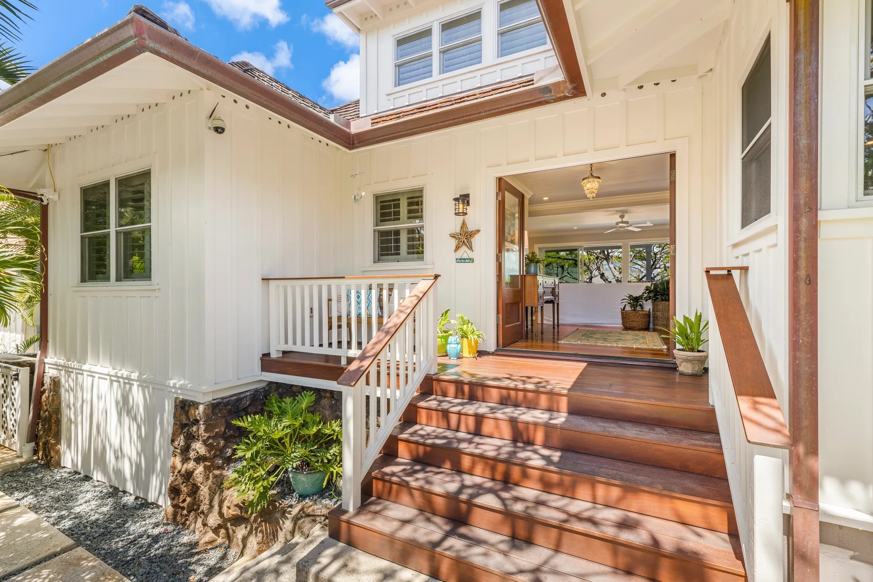 A raised wooden porch leads into a bright home through an open doorway.
