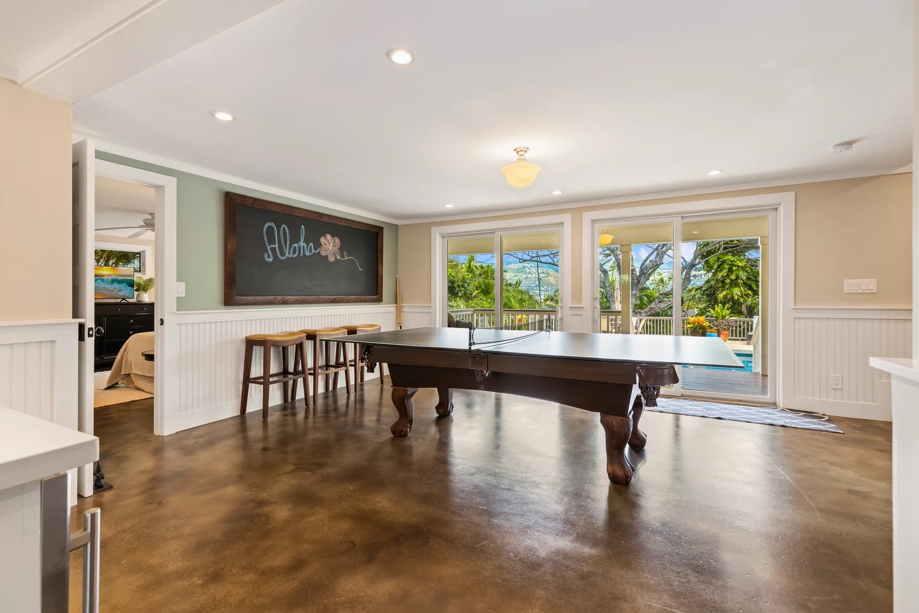 A bright game room with a large billiards table and windows overlooking greenery.