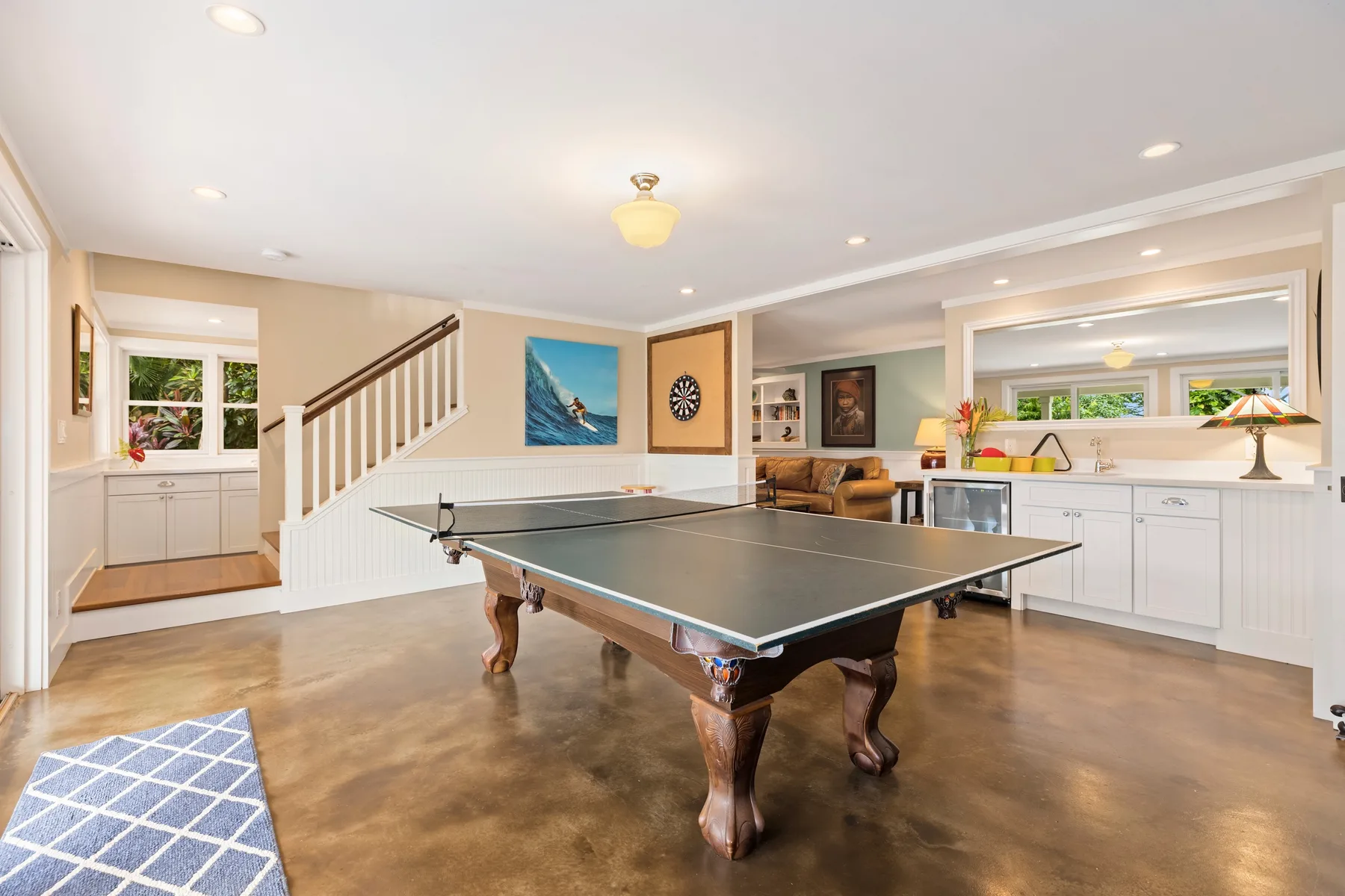 A basement recreation room with a ping-pong table and a seating area.