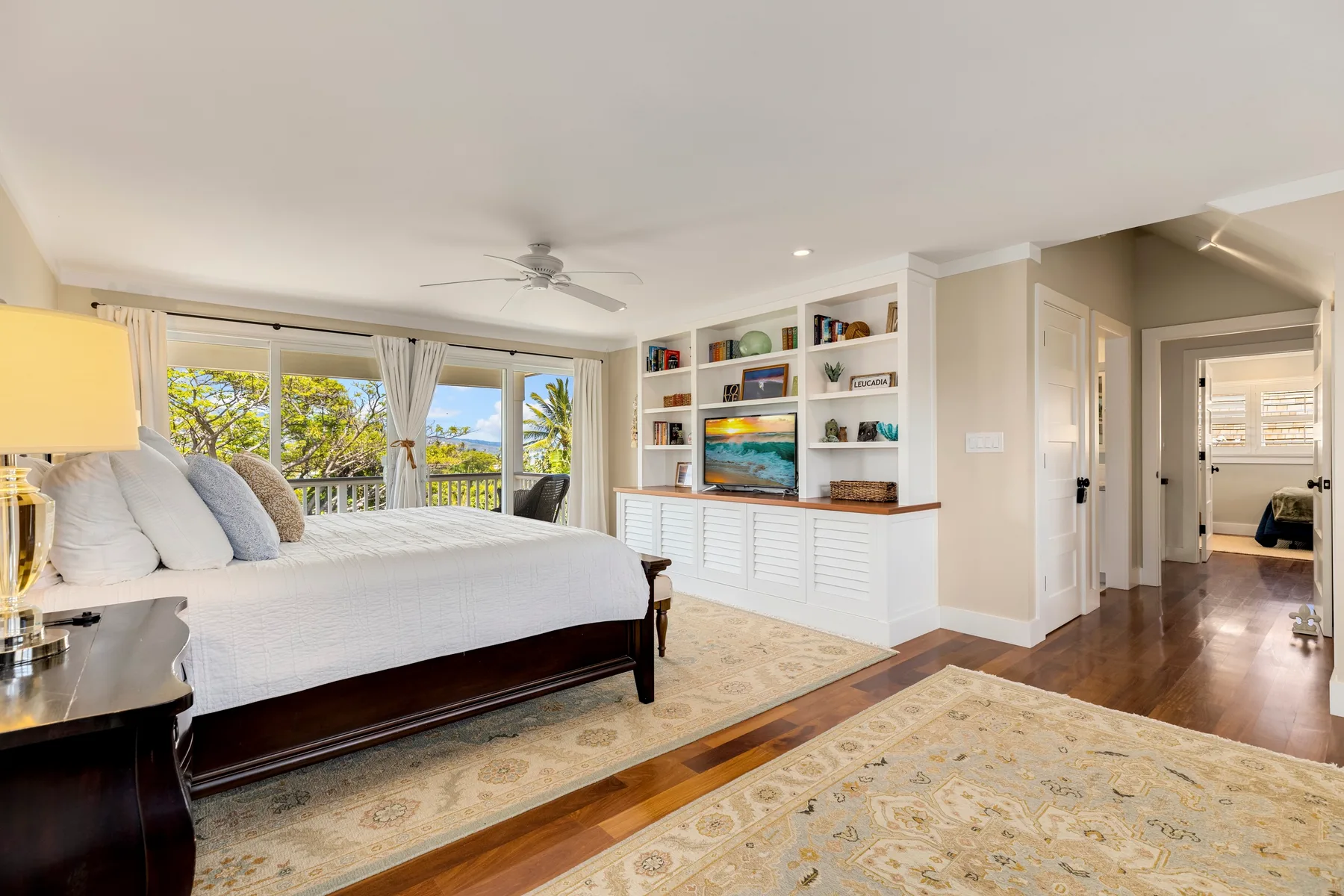 A bright bedroom with a large bed and built-in shelves beside the windows.
