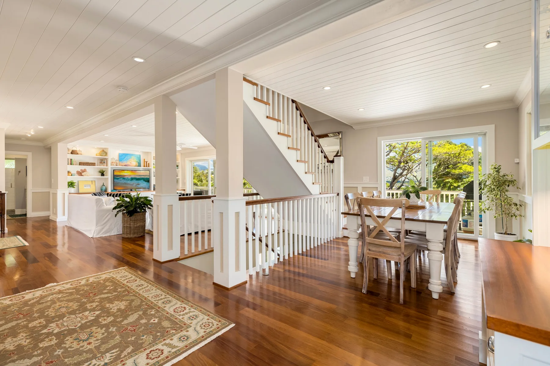 Open dining and living area with a wooden table beside a staircase.