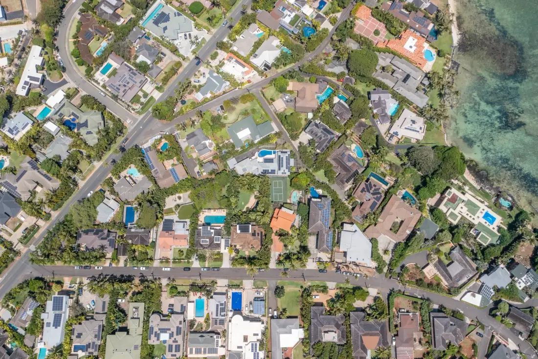Aerial view of a coastal residential neighborhood with homes and swimming pools.
