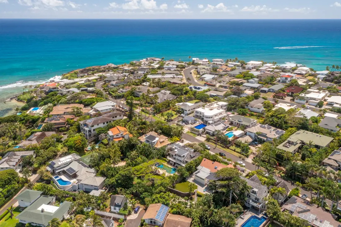 Aerial view of a coastal neighborhood beside the turquoise ocean.