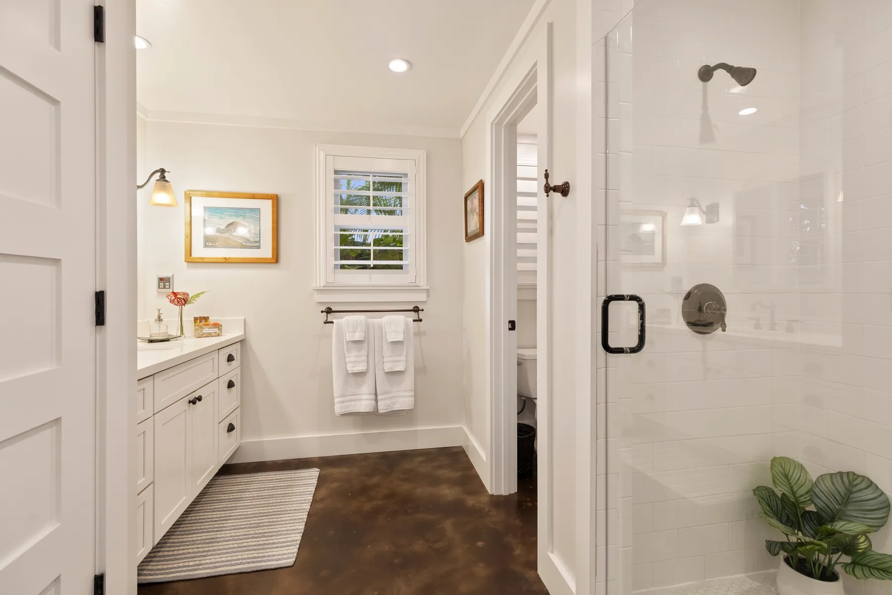 A bright bathroom with a vanity, window, and glass-enclosed shower.