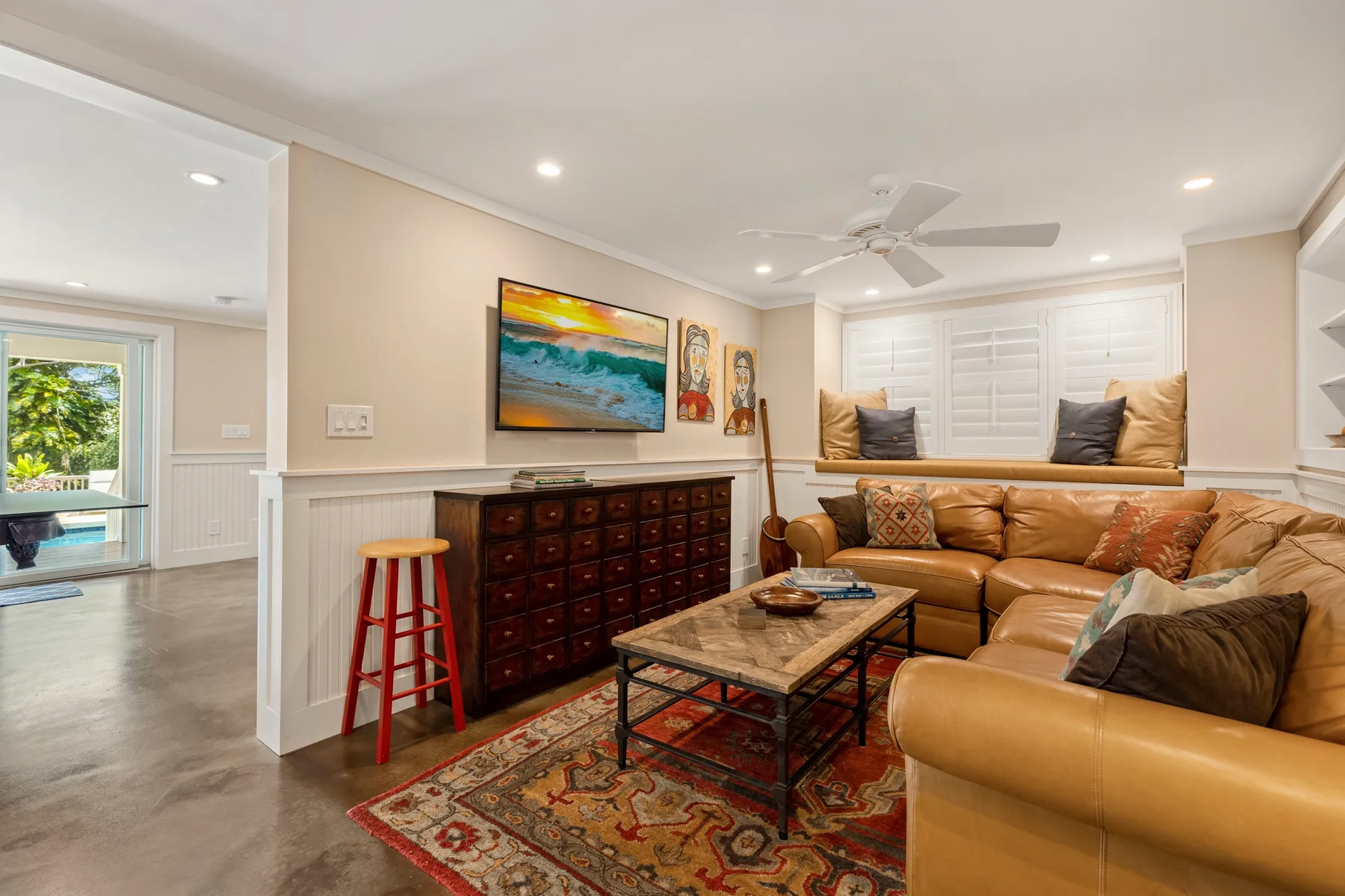 A living room with tan seating, a coffee table, and a television.