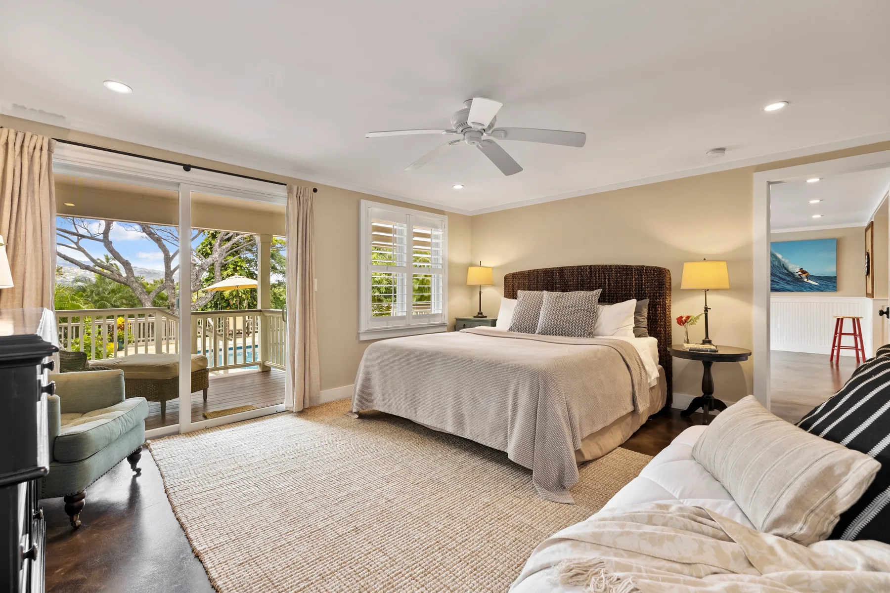 A bright bedroom with a large bed, a seating area, and glass doors opening to a balcony.