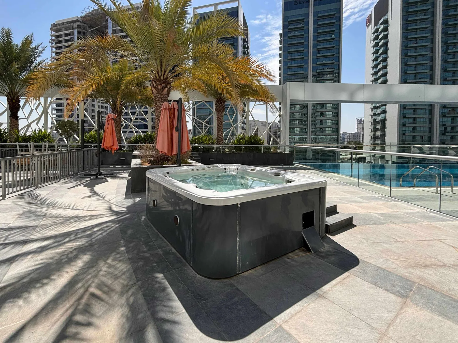 An outdoor terrace features a raised hot tub beside a glass railing.