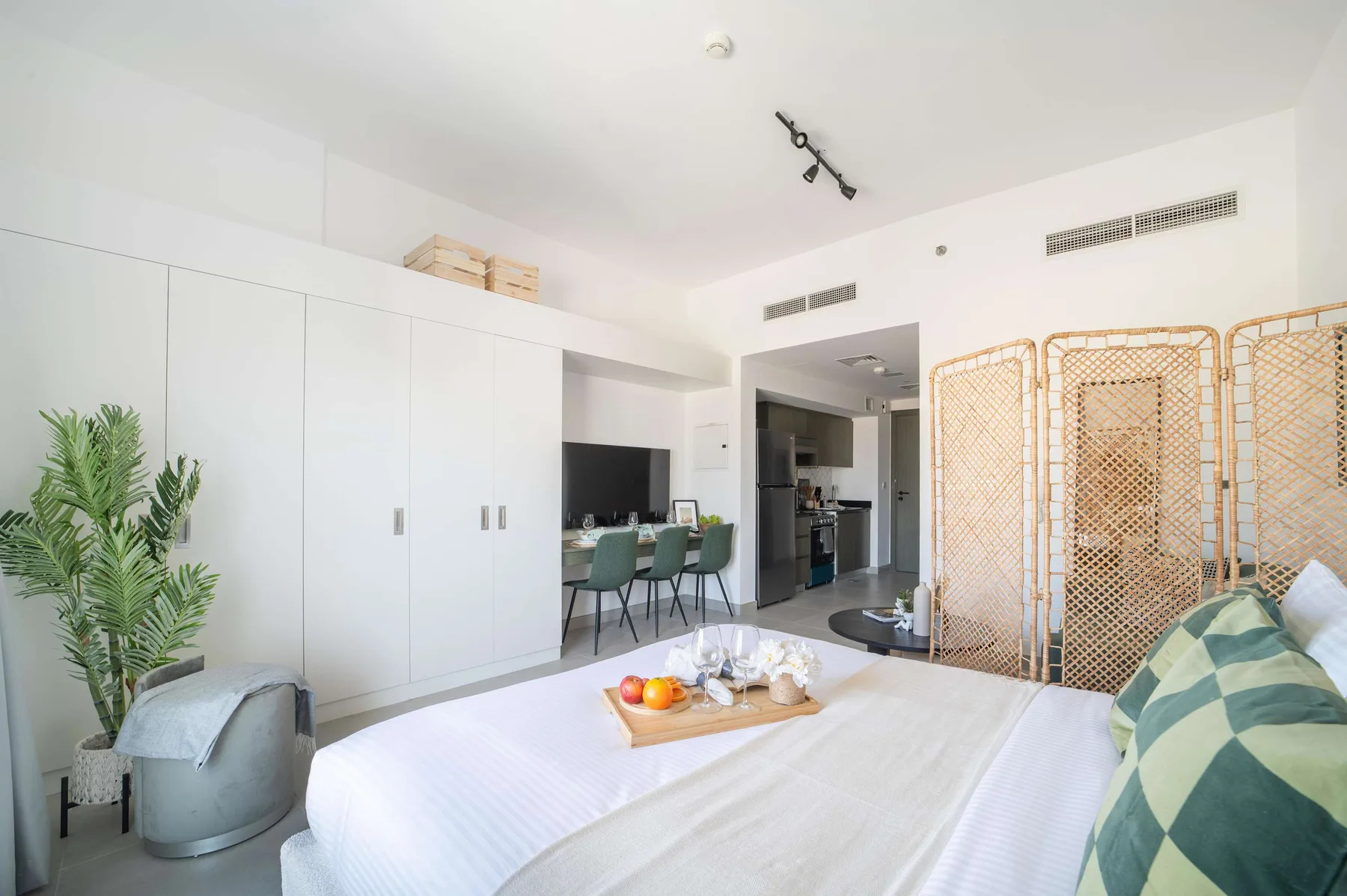 A bright bedroom with a bed, built-in storage, and a dining area.