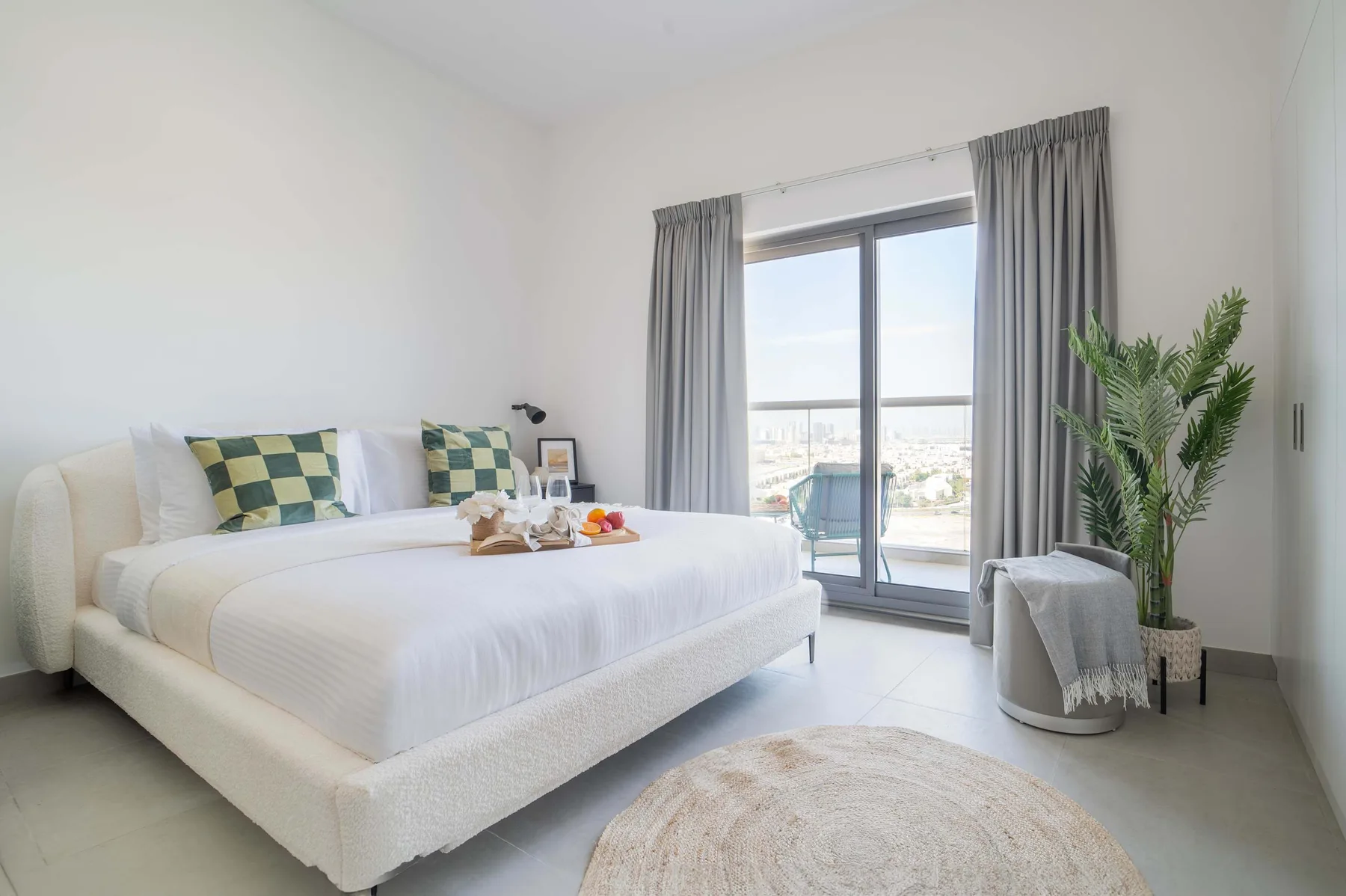 A bright bedroom with a neatly made bed beside a large window.