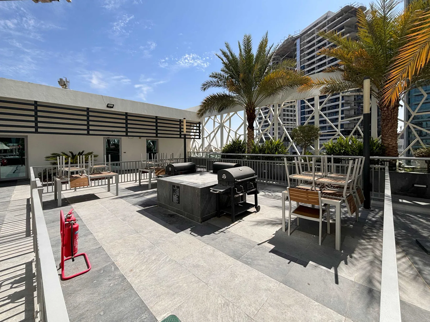 An outdoor dining terrace with tables, seating, and a barbecue grill.