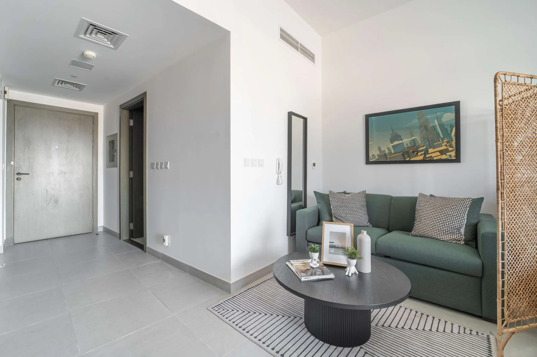 A living area with a green sofa, coffee table, and framed wall art.