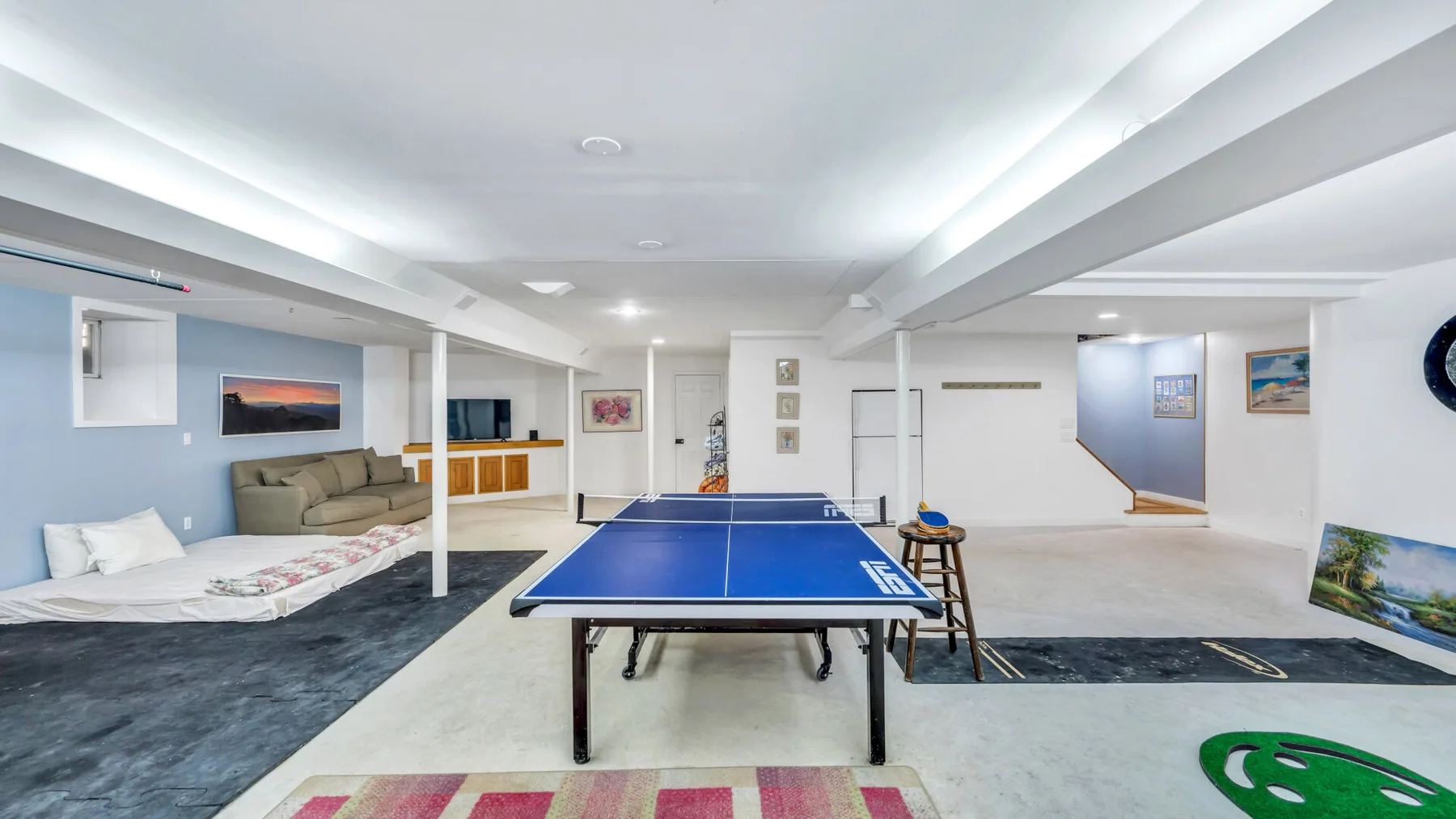 Una sala de recreación en el sótano con una mesa de ping-pong y asientos.