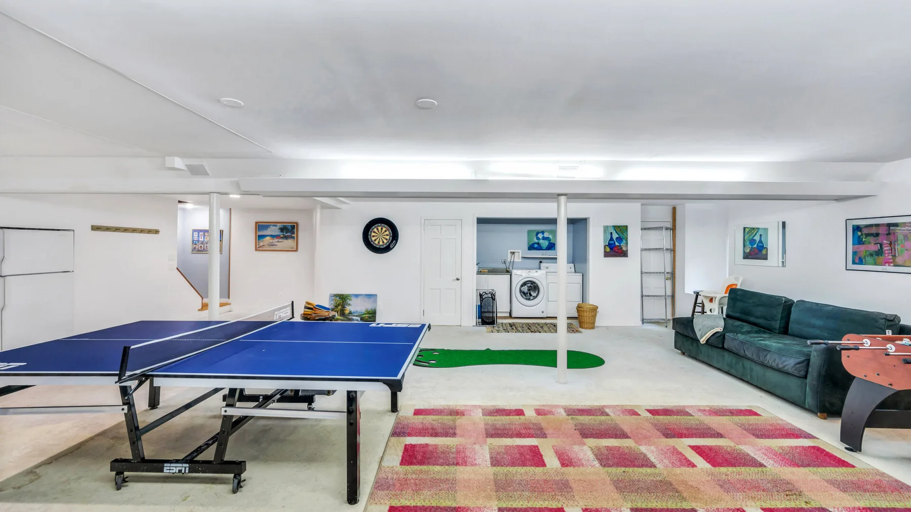 Una sala de recreación tiene una mesa de ping-pong azul y asientos verdes.