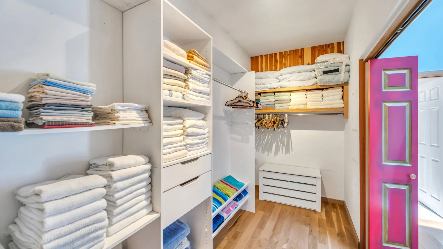 Un luminoso cuarto de ropa de cama con estantes de toallas y ropa dobladas.